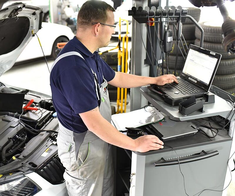 car mechanic maintains a vehicle with the help of a diagnostic computer - modern technology in the car repair shop